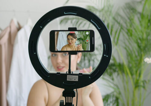 a woman recording herself using a smartphone and a ring light